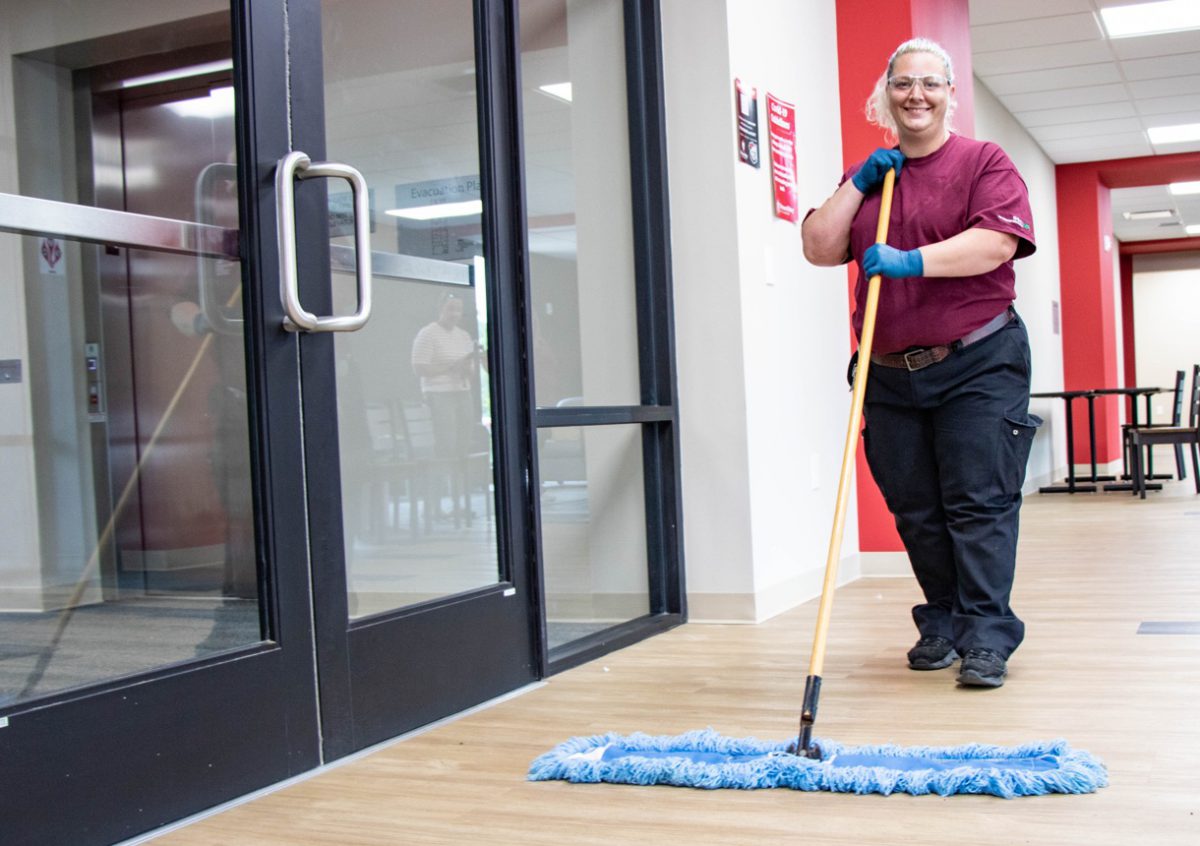 smiling custodian mopping floor of school